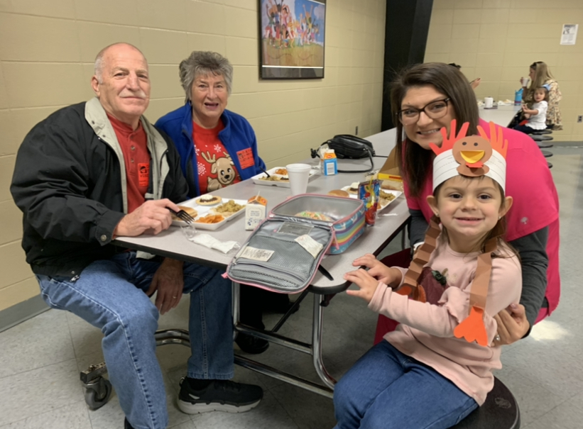 Grandparents and Mother with student wearing turkey hat