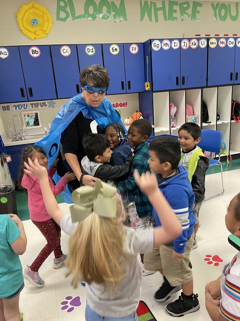 kids gathered around adult dressed in a cape and shirt with 0 on it
