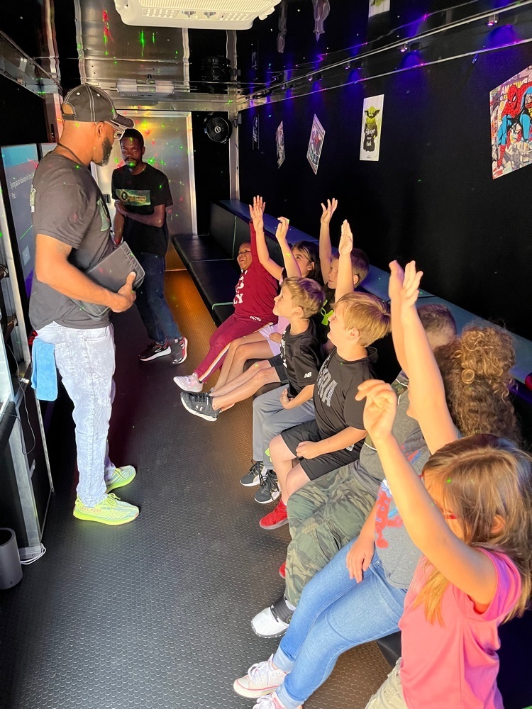 students raising their hands in gaming trailer